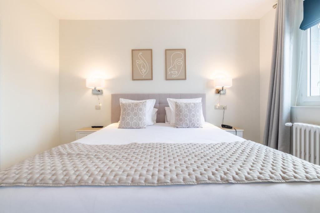 - une chambre avec un lit blanc et 2 oreillers dans l'établissement Hôtel Échappée en Baie - Parking privé gratuit dont forfaits bornes électriques réservable, à Saint-Valery-sur-Somme