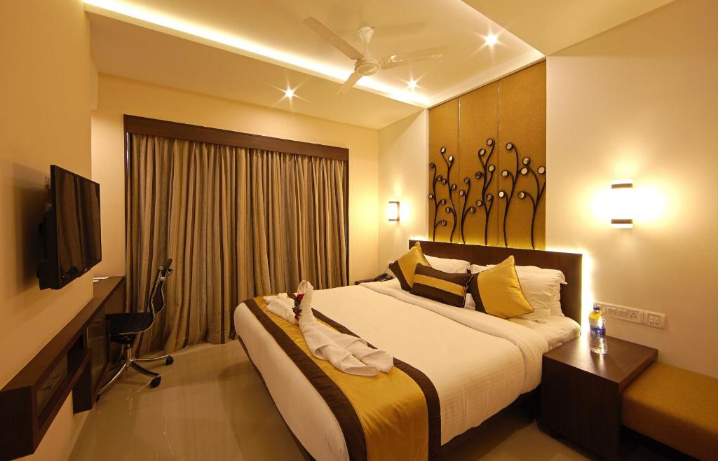 - une chambre avec un grand lit et une télévision dans l'établissement Golden Fruits Business Suites, à Chennai