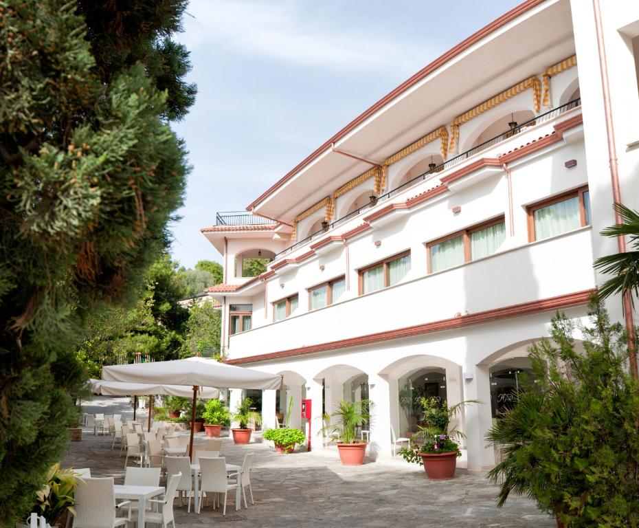 a large white building with tables and chairs at Hotel Paradiso in Santa Maria di Castellabate