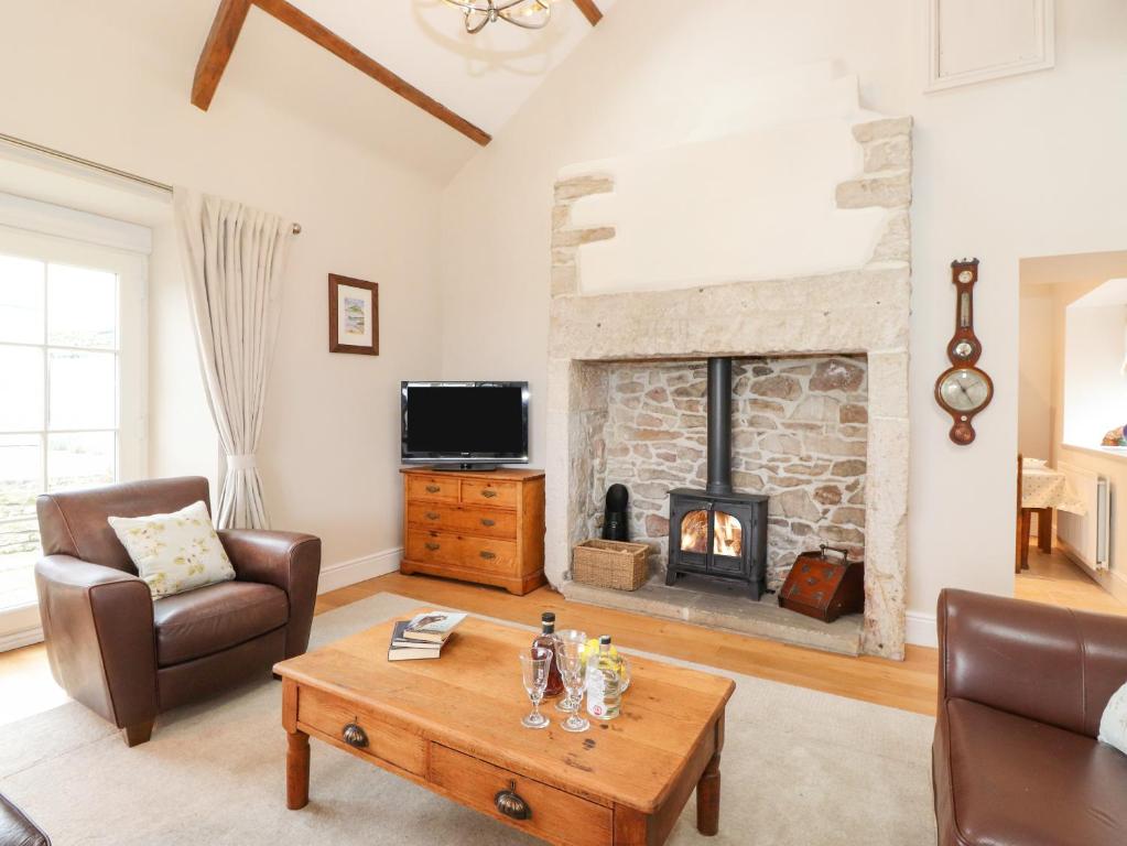 a living room with a fireplace and a table at Farnelea in Chathill