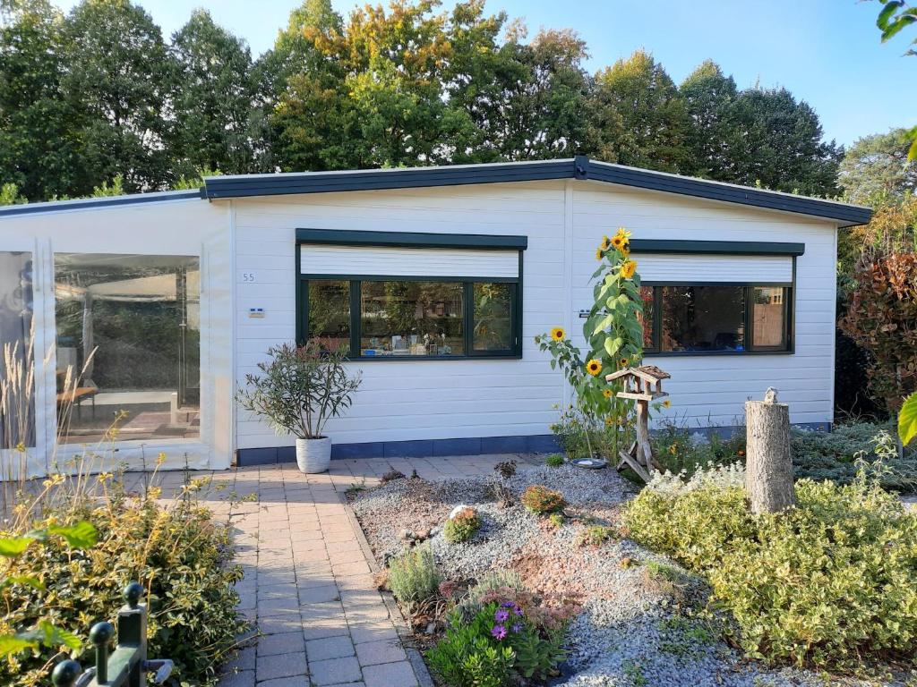 un cobertizo blanco con ventanas en un jardín en Chalet M & J, en Heel