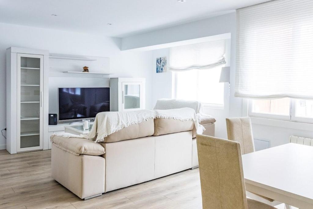 a living room with a white couch and a television at MyHouseSpain - Piso en centro Gijón a pocos minutos de las playas in Gijón