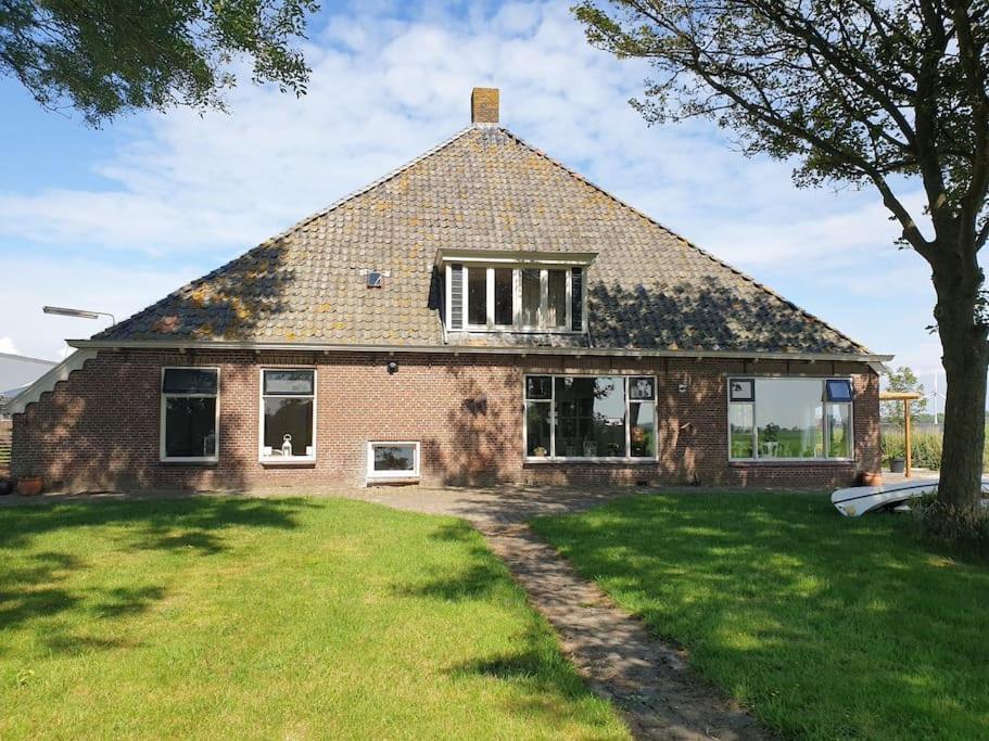 een groot bakstenen huis met een grasveld bij Akkerhorst boerderij Lollum in Friesland. in Lollum