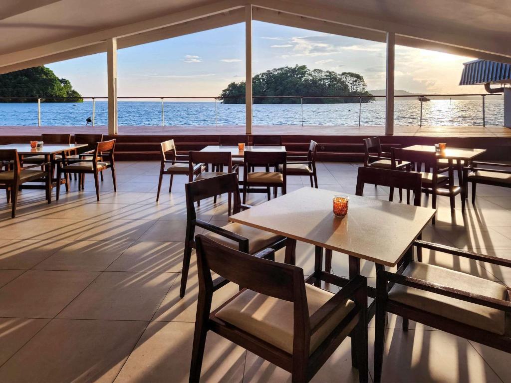 スバにあるノボテル スバ ラミ ベイのテーブルと椅子が備わるレストランで、水辺の景色を望めます。