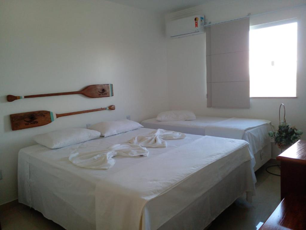 two beds with white sheets in a room at Hotel Rio Acaraí in Camamu
