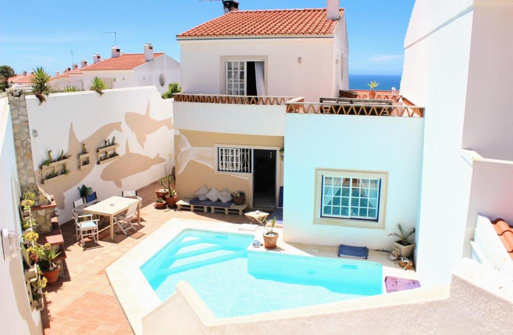 a villa with a swimming pool in front of a house at Ericeira Soulsurfers Guesthouse in Ericeira