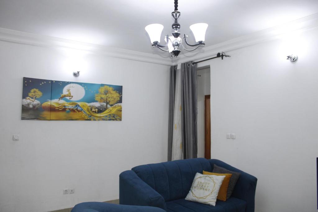 sala de estar con silla azul y lámpara de araña en Cozy Bay, en Douala