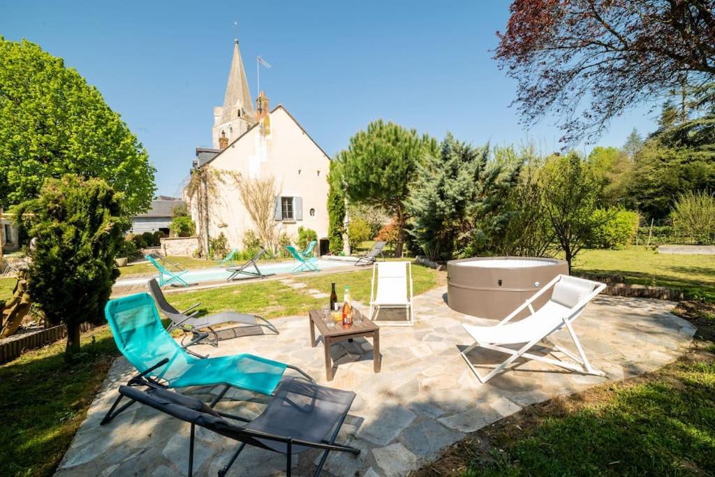 un patio con sillas, mesa y bañera en Le Clos du Tilleul Fabuleuse propriété 15 à 30 Pers Piscine au coeur d'un charmant village en Thilouze