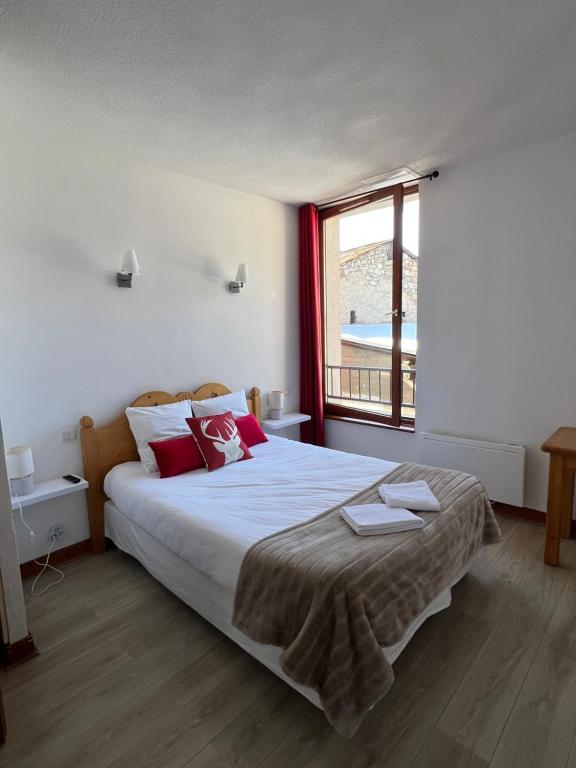 a bedroom with a large bed with red pillows and a window at Auberge La Cascade in Avrieux