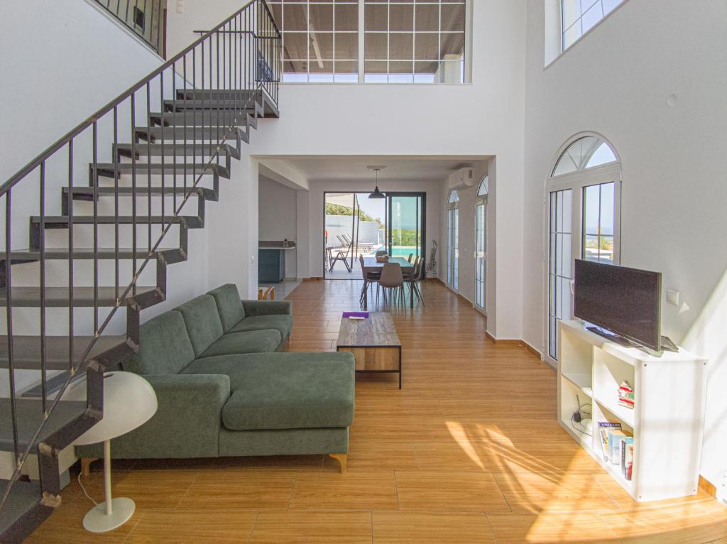 salon z zieloną kanapą i schodami w obiekcie Modern villa with infinity pool close to the sea w mieście Tavronitis