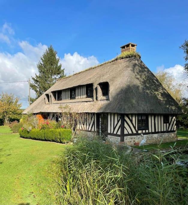 une maison ancienne avec un toit de chaume sur un champ dans l'établissement Maison et dépendance haut de gamme proche de Deauville-Trouville, à Les Authieux-sur-Calonne
