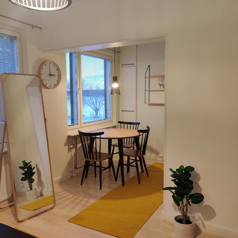 a dining room with a table and chairs and a clock at Huoneisto rantabulevardilla, 1-4 hengelle in Savonlinna