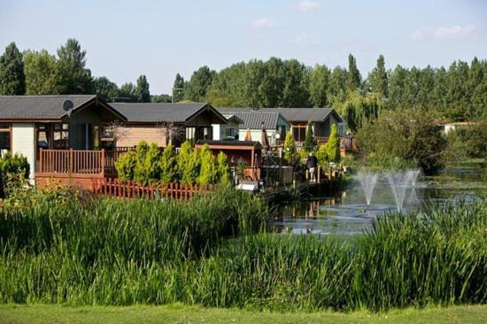 a group of houses on a river with a pond at Impeccable 3 bedroom lodge pet friendly in Northampton