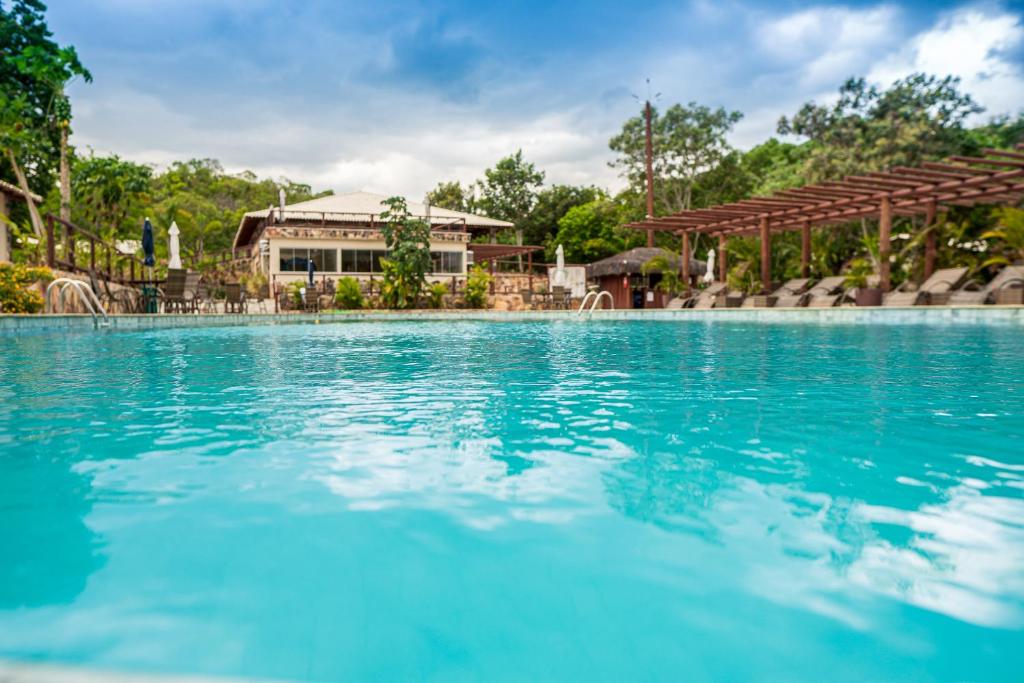 a large swimming pool with a house in the background at Pousada Renascer Park in Pirenópolis