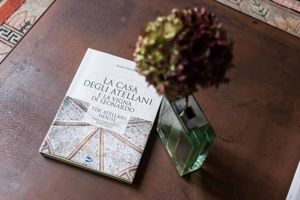 um livro sentado numa mesa ao lado de um vaso de flores em Atellani Apartments em Milão