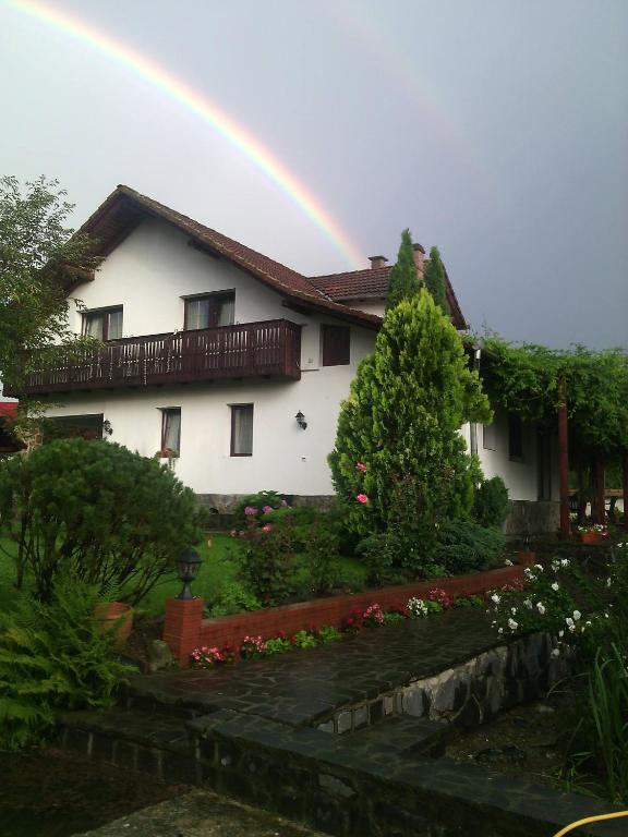 a rainbow over a white house with a garden at Apartvilla Serbota in Porumbacu de Sus