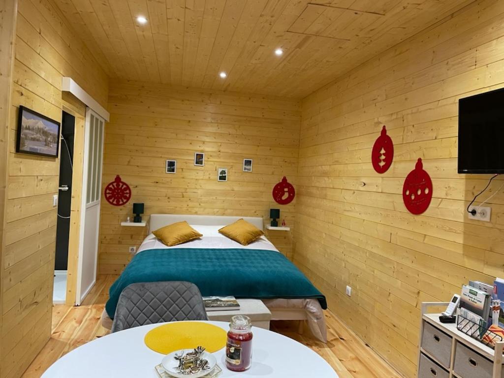 1 dormitorio con 1 cama en una habitación de madera en Le petit gîte des 4 saisons en Cézens