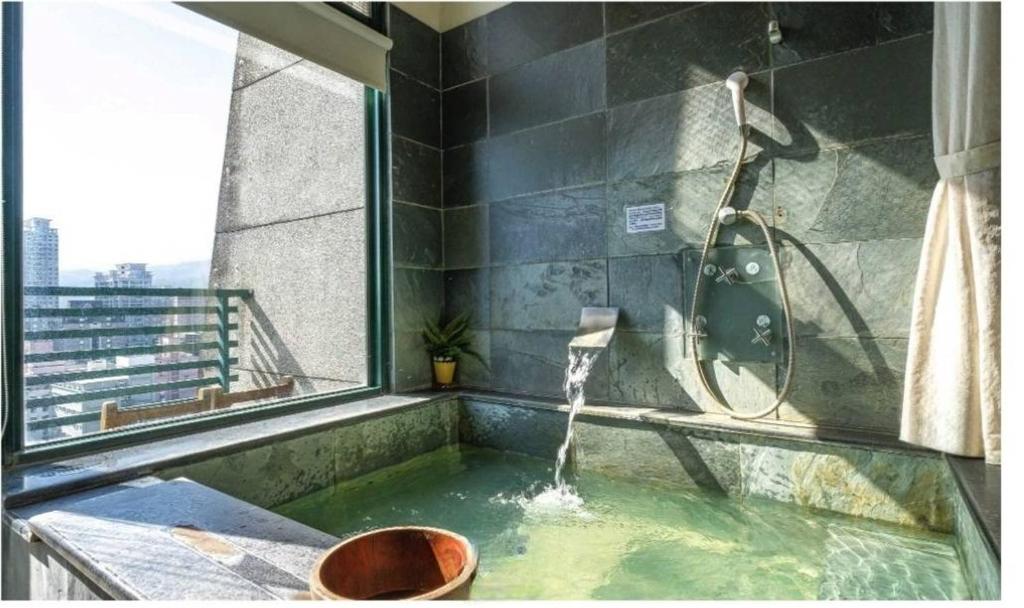 a bathroom with a bath tub with a shower at 泉泉溫泉民宿 in Jiaoxi