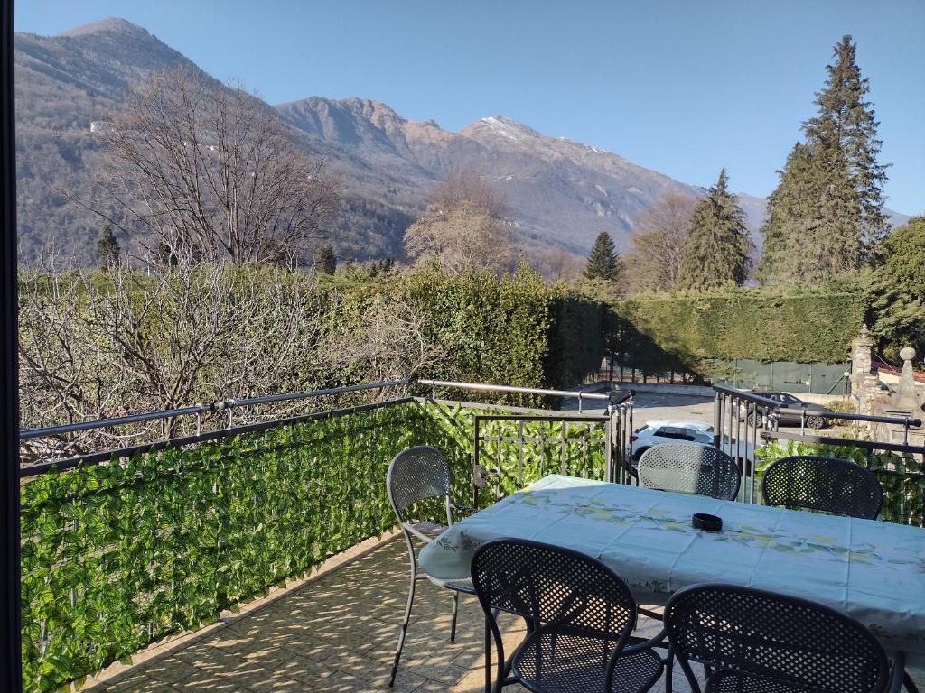 uma mesa e cadeiras numa varanda com montanhas ao fundo em Casa Terrazzo Panoramico em Cannobio