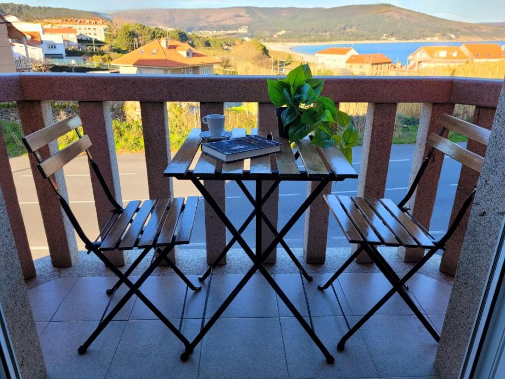 a table and two chairs on a balcony at Camiño á praia in Fisterra