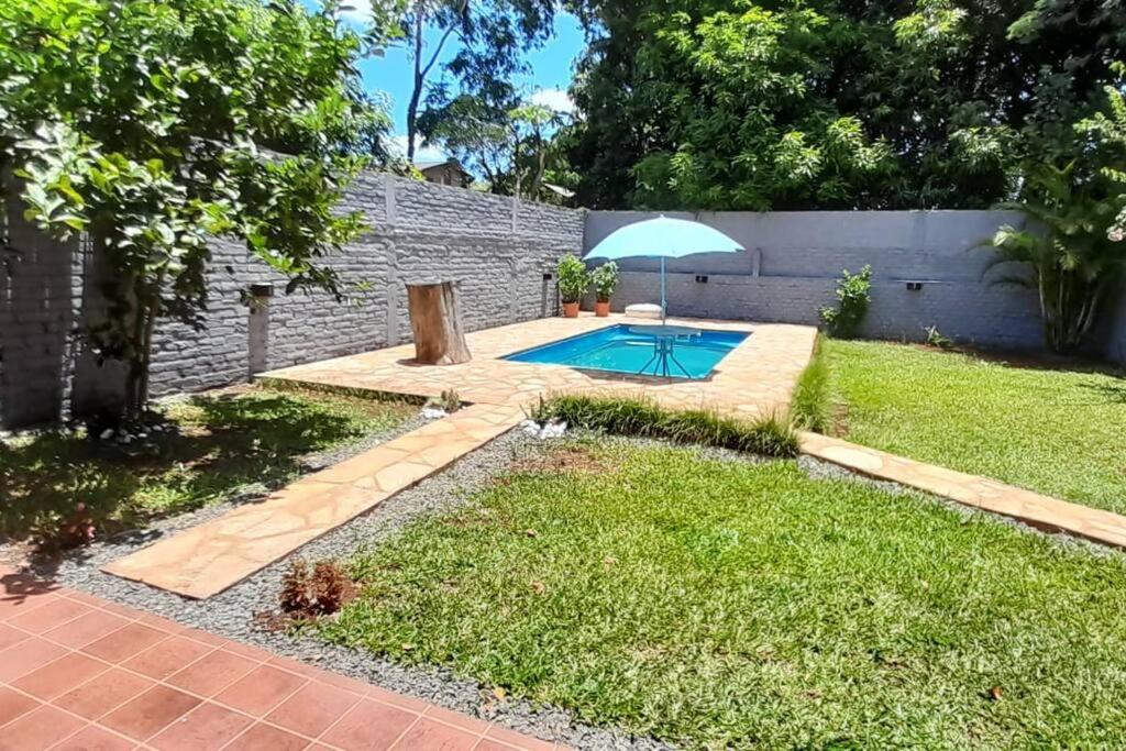 un patio trasero con piscina y sombrilla en Karina House en Jardín América