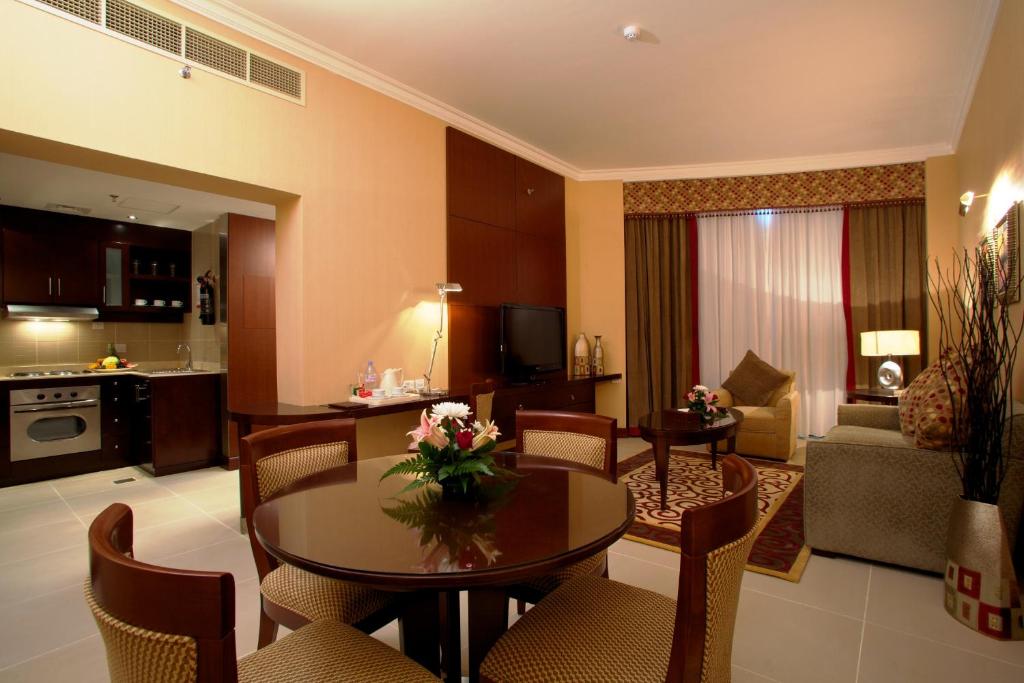 a living room with a table and chairs and a kitchen at Concorde Hotel Fujairah in Fujairah