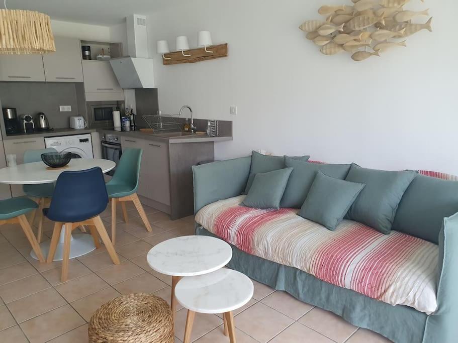 a living room with a blue couch and a kitchen at Mignon appartement en résidence avec piscine in Biscarrosse