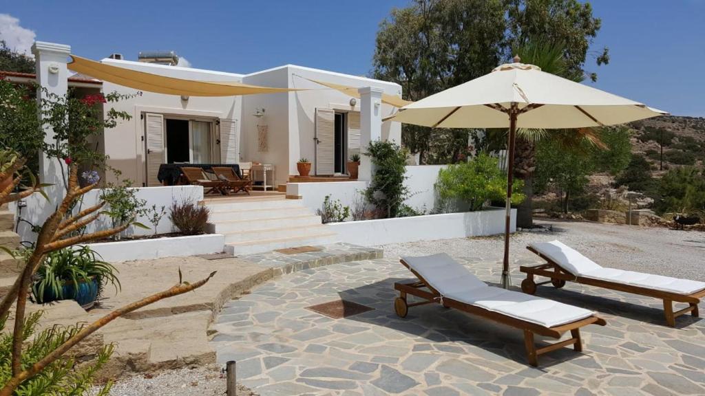 a house with two chairs and an umbrella at Tranquil Villa with Sea view in Ammopi Karpathos in Amoopi