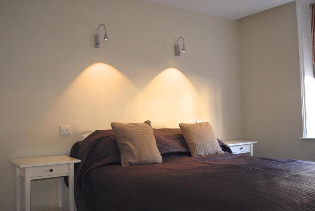 een slaapkamer met een bed met verlichting aan de muur bij Short Stay Bungay in Bungay