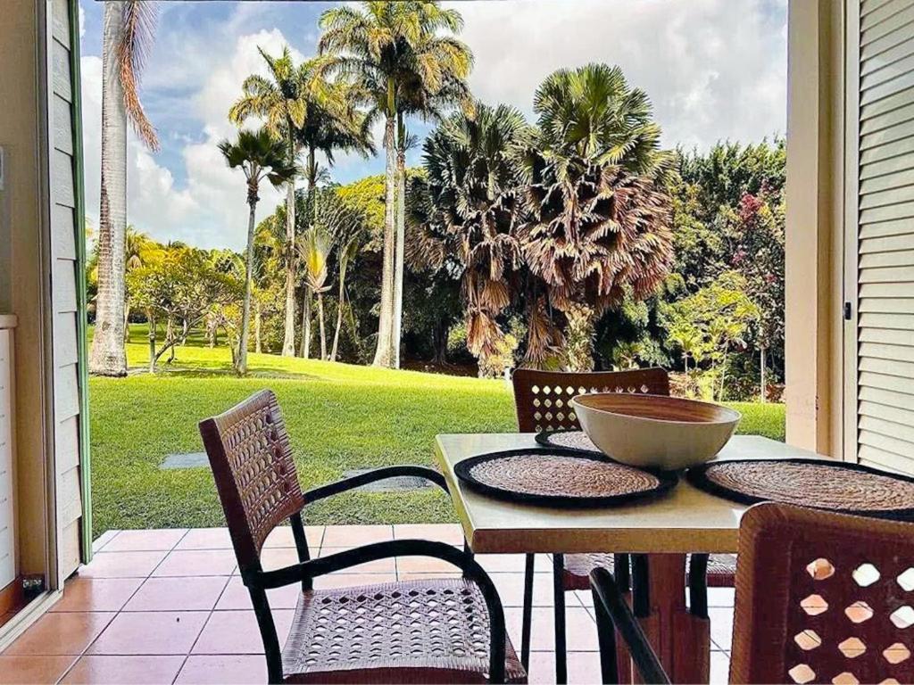 a porch with a table and chairs and palm trees at Pierre & Vacances Antigua 03 in Sainte-Luce