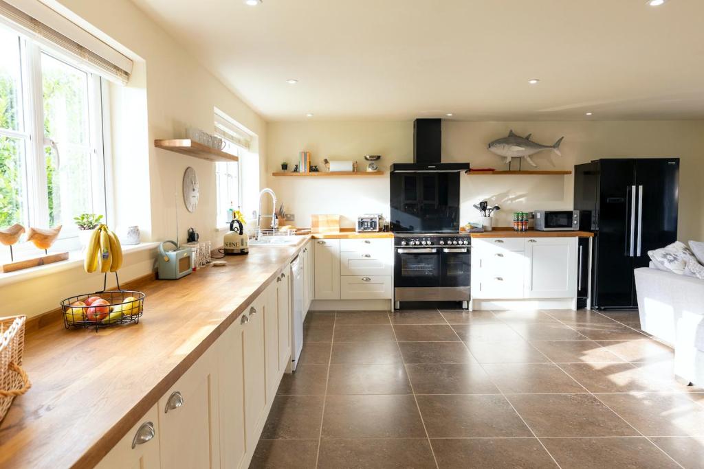 a kitchen with white cabinets and a black refrigerator at Luxury 5 bedroom house - sleeps 10 in Colkirk