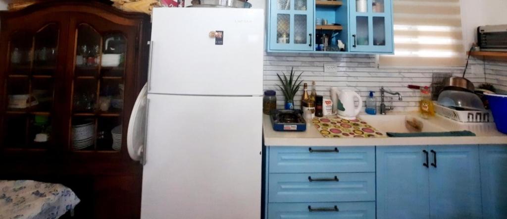 een witte koelkast in een keuken met blauwe kasten bij מול חרמון in Majdal Shams