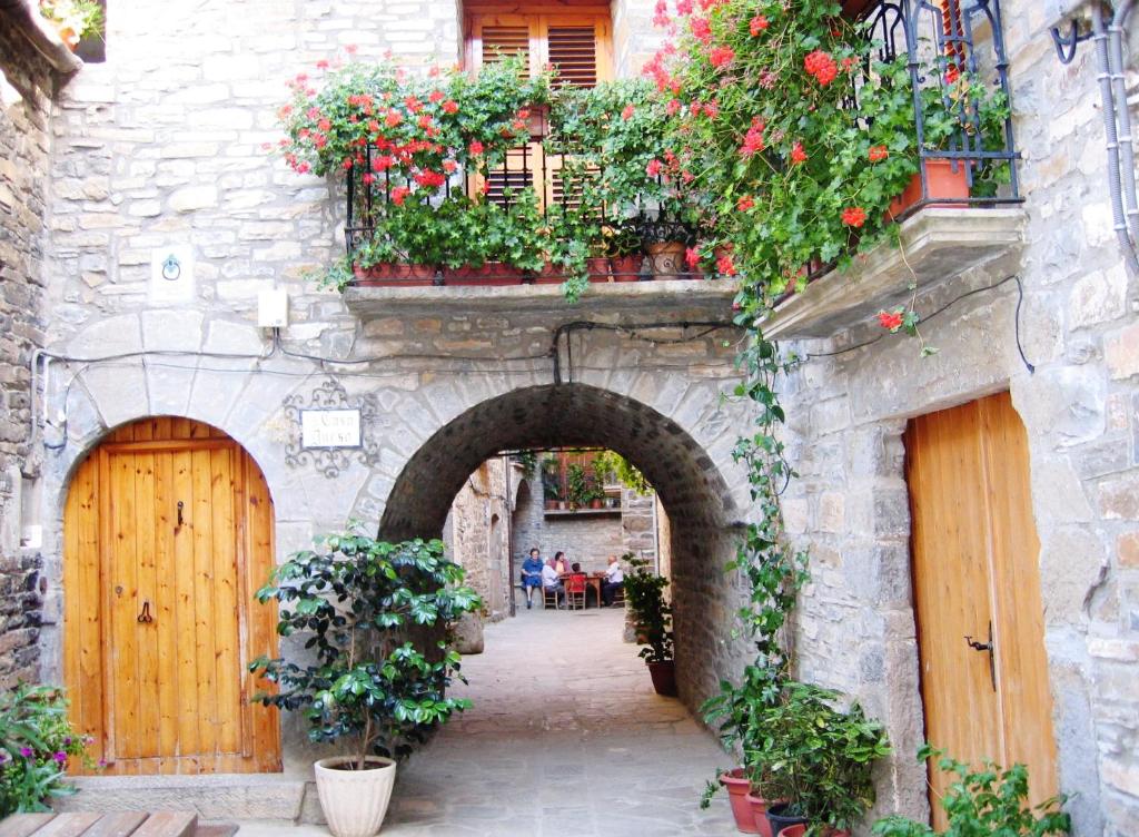 an alley in an old stone building with flowers at Casa Dueso in El Pueyo de Araguás