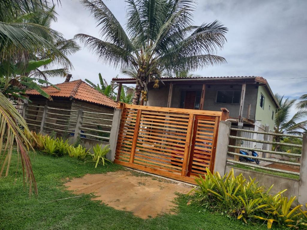 a wooden fence in front of a house with a palm tree at Casa de praia em Canavieiras in Canavieiras