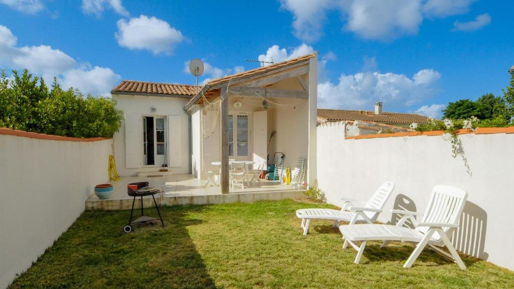 拉弗洛特的住宿－Maison récente, à proximité du port de La Flotte，一个带白色椅子的院子和房子