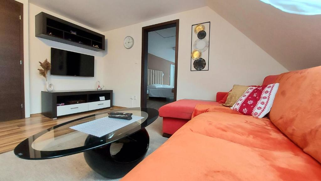 Apartmán Tajov pre 5-6 osôb, privatne parkovanie a terasa في Tajov: غرفة معيشة مع أريكة حمراء وطاولة زجاجية