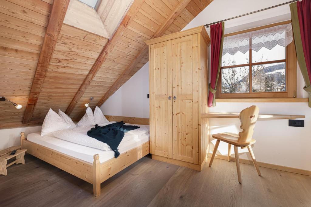 a bedroom with a bed and a chair in a room at Chalet Winklwiese in Valdaora
