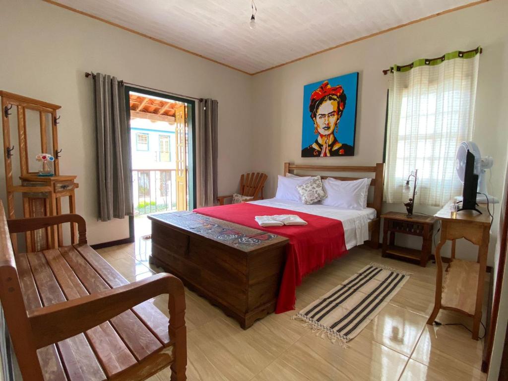 ein Schlafzimmer mit einem Bett mit einer roten Decke in der Unterkunft Pousada Artes Evano in Bichinho