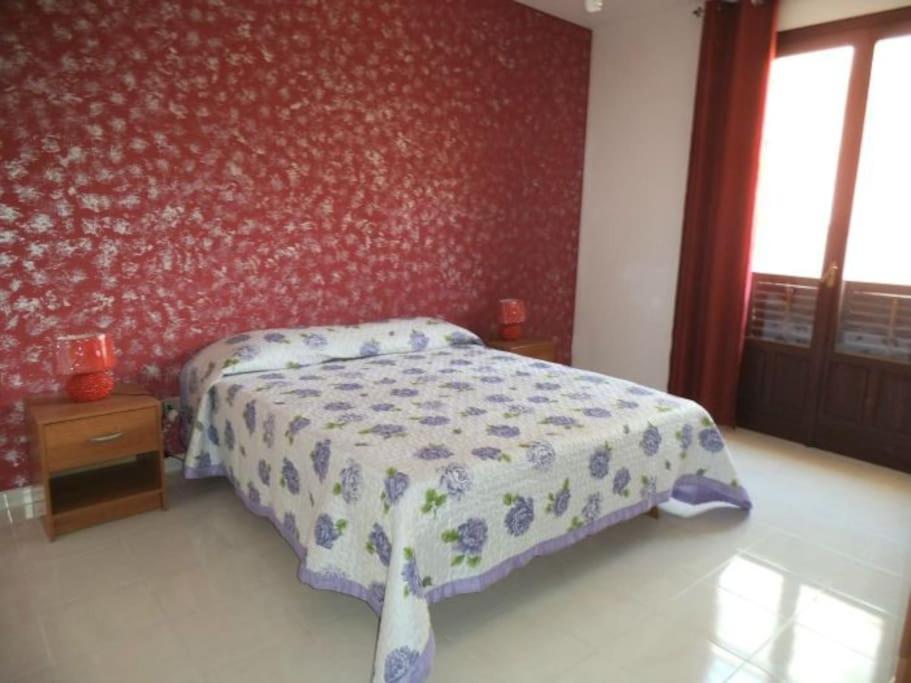 ein Schlafzimmer mit einem Bett und einer roten Wand in der Unterkunft Casa MoDerna 25SX in Castellammare del Golfo