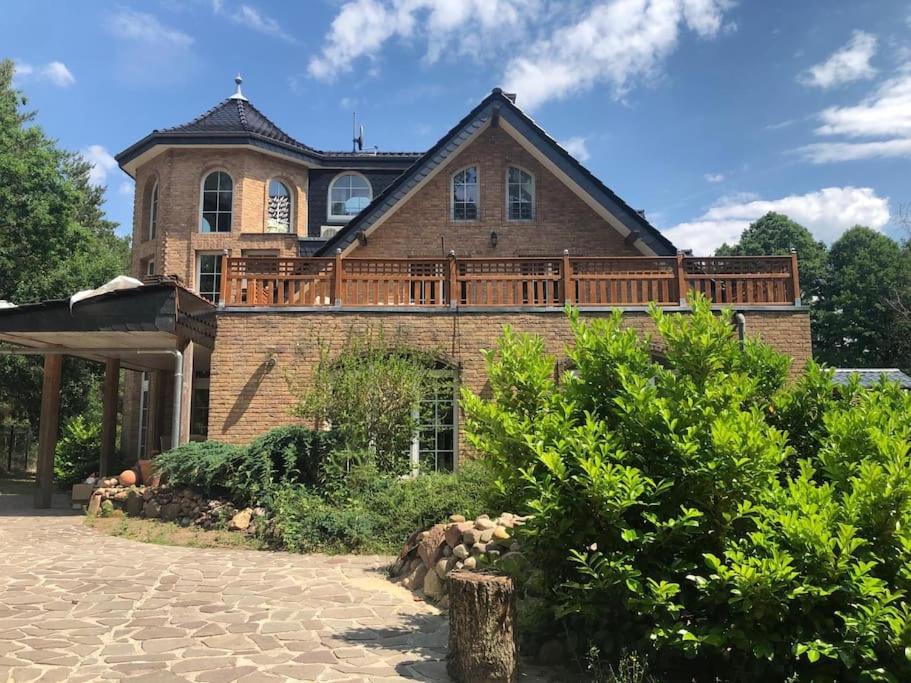 ein großes Backsteinhaus mit einer großen Terrasse in der Unterkunft Seeblick eins im Waldschlößchen in Wendisch Rietz