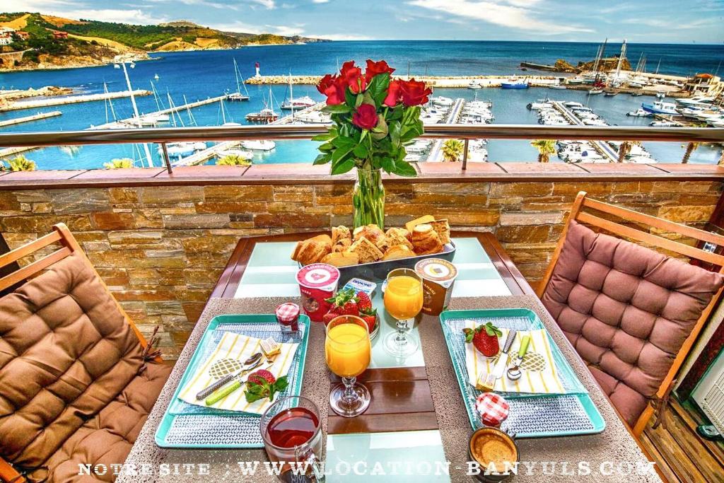 a table with food and a vase of flowers on a balcony at Location de charme de Thierry BOURGAIT in Banyuls-sur-Mer