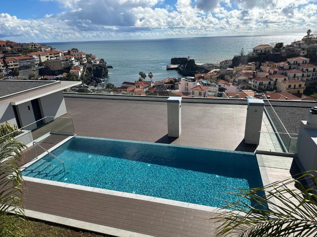 a swimming pool on the roof of a house with the ocean at Deluxe Bay View in Câmara de Lobos