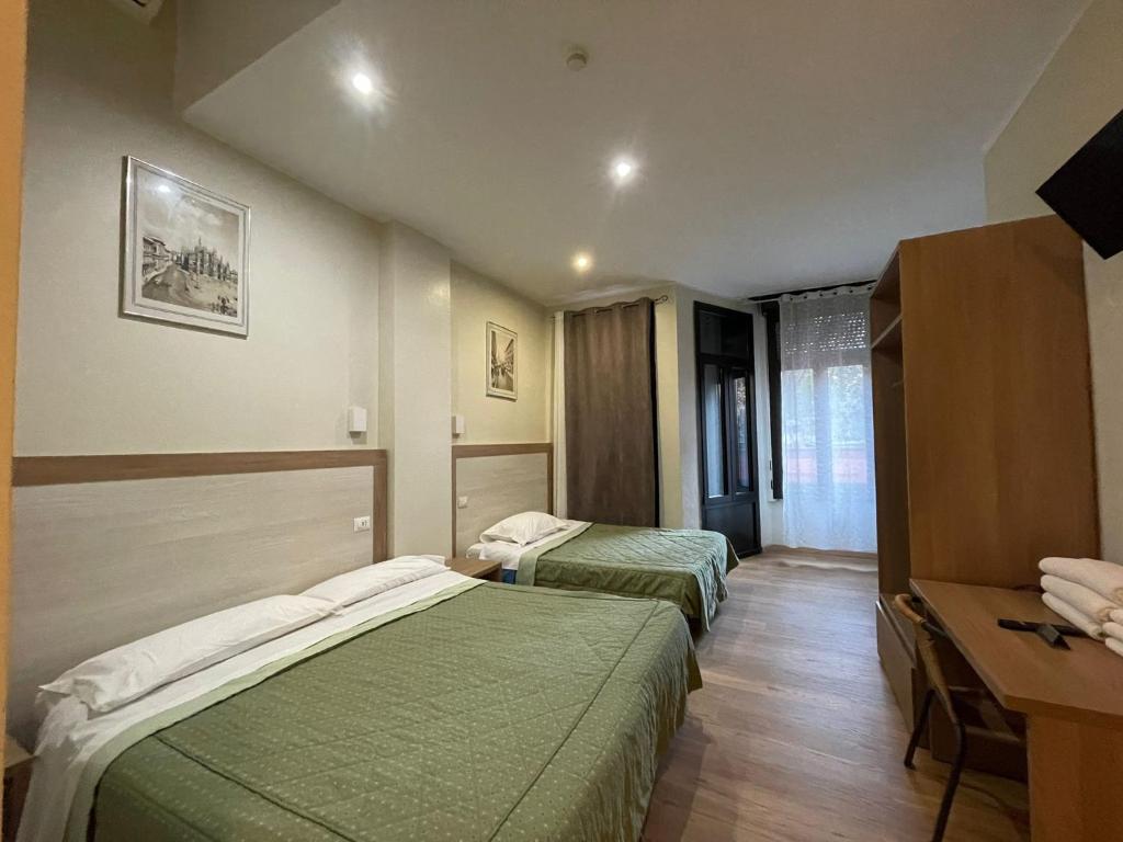 a hotel room with two beds and a desk at Hotel 26 in Milan