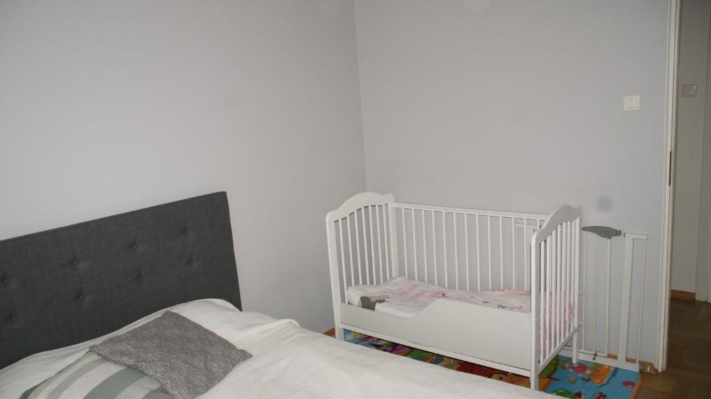 um berço branco num quarto com uma cama em Apartament Alutka em Cracóvia