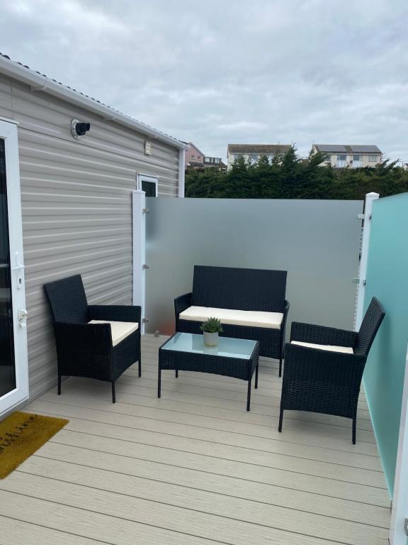 eine Terrasse mit 2 Stühlen, einem Tisch und einem Sofa in der Unterkunft Dave and Deb's Place Beverley Bay in Paignton