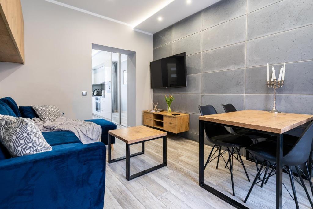 een woonkamer met een blauwe bank en een tafel bij Apartament Arena Gliwice Budget in Gliwice