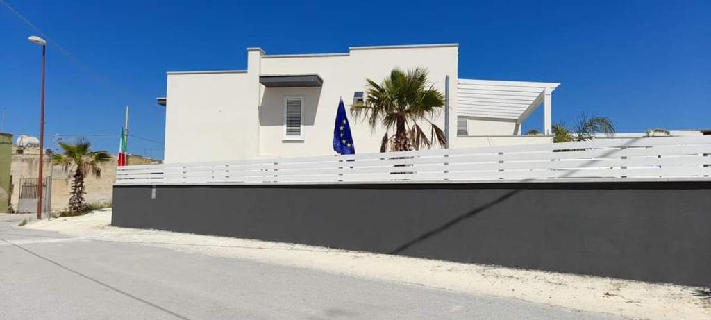 um edifício branco com uma cerca branca e uma bandeira azul em Casa Vacanze "O Timpune" em Petrosino