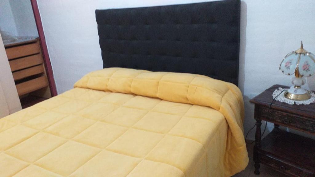 1 dormitorio con cama amarilla y cabecero negro en A 4 cuadras del ORFEO Alto verde 2 dormitorios en Córdoba
