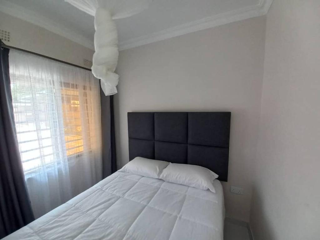 Schlafzimmer mit einem weißen Bett und einem Fenster in der Unterkunft Kasuda Rooms - Cosy self contained rooms in Livingstone