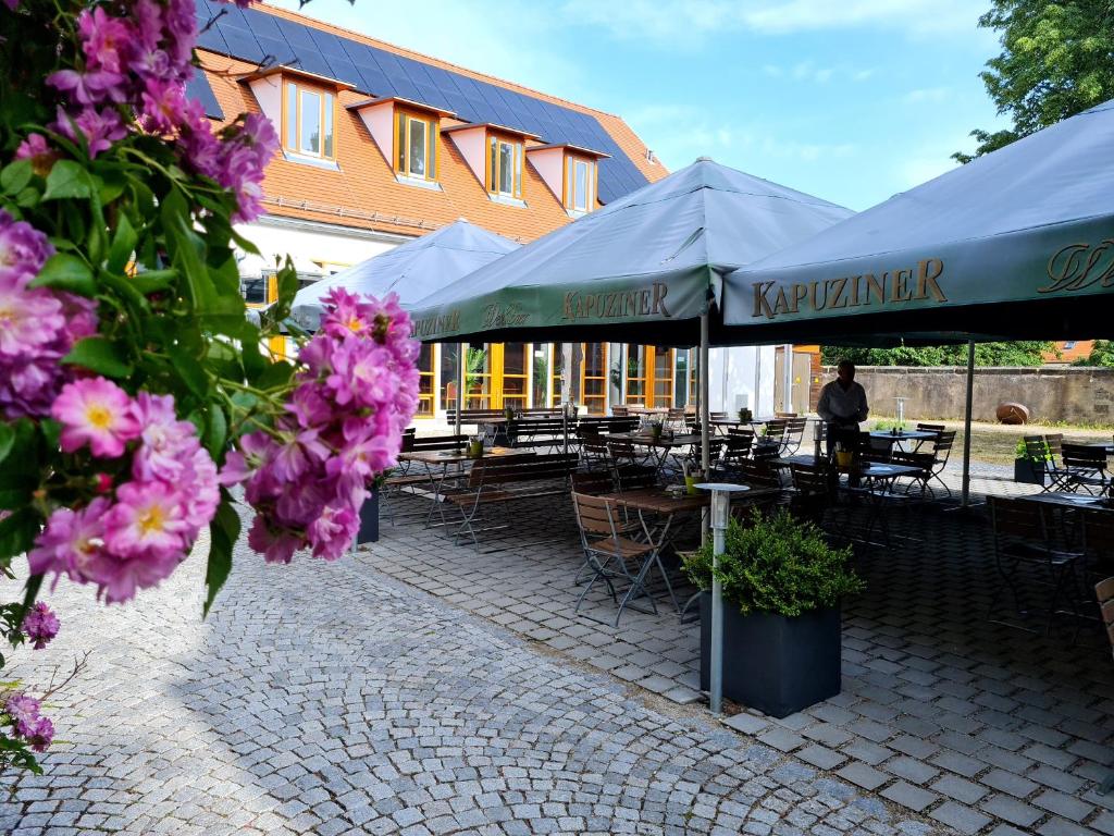 un patio con mesas, sillas y flores púrpuras en Gasthof zur Post, en Neunkirchen am Brand